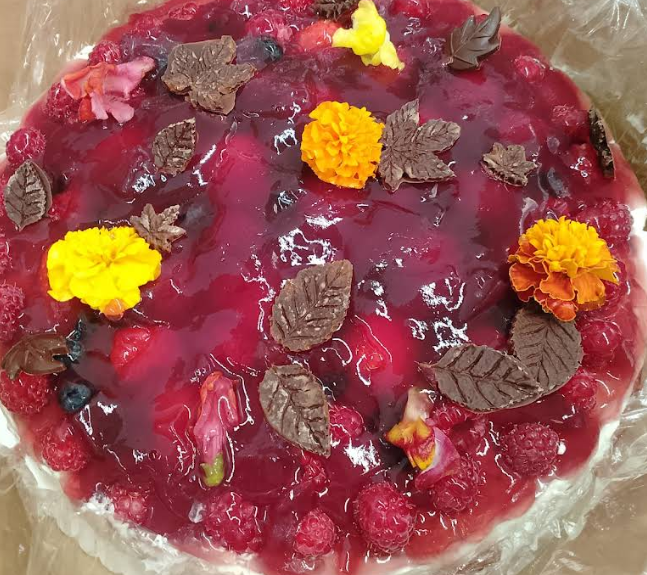 Glutenfreie Beerentorte mit essbaren Blüten und Schokoladenblättern